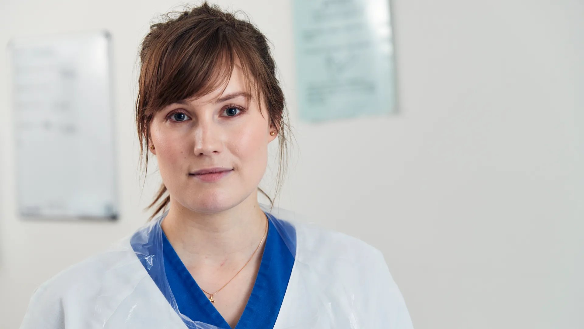 En kvinna i vit labbrock med ett blått band runt halsen.