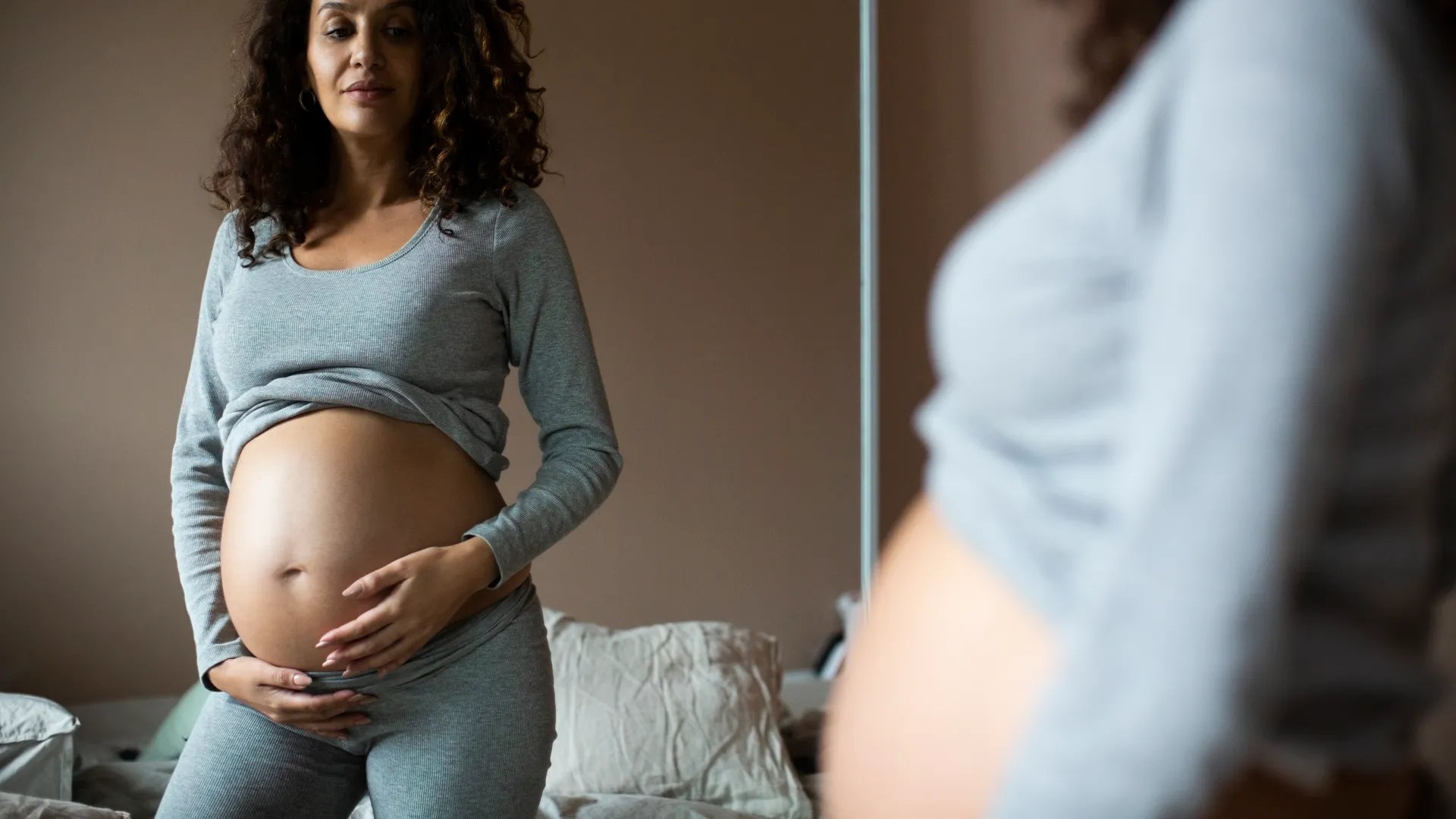 En gravid kvinna står framför en spegel.